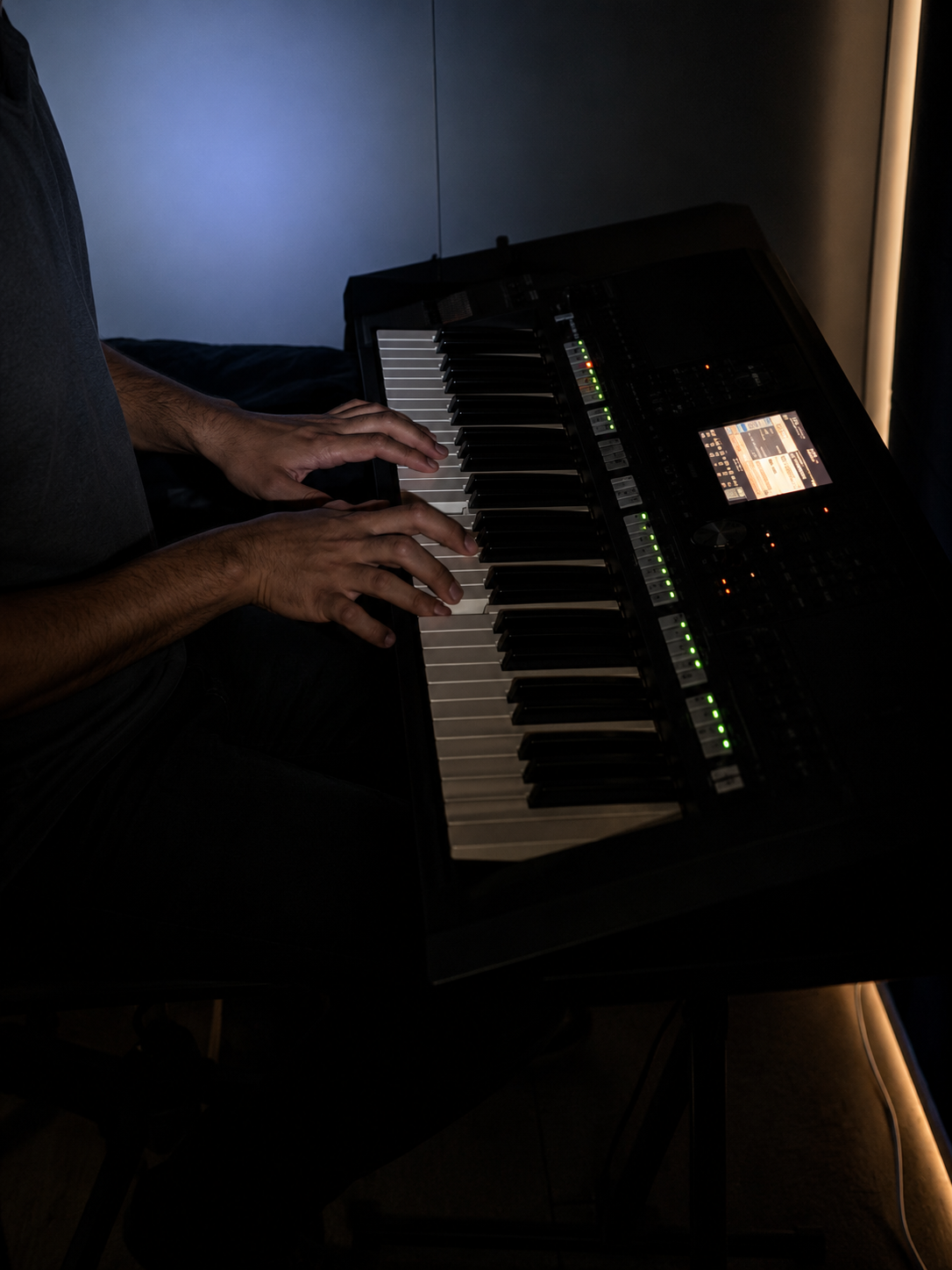 An abstract, close-up shot of a hand playing an electronic keyboard in a dark room under moody lighting